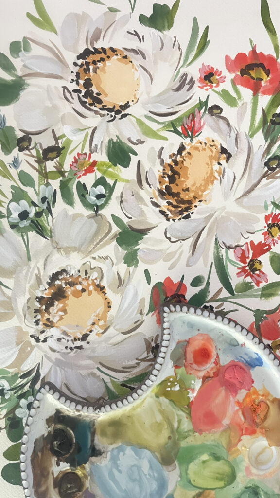 A vibrant watercolor painting of large white and peach flowers with green leaves and red accents. A ceramic palette with colorful paint sits in the bottom corner.